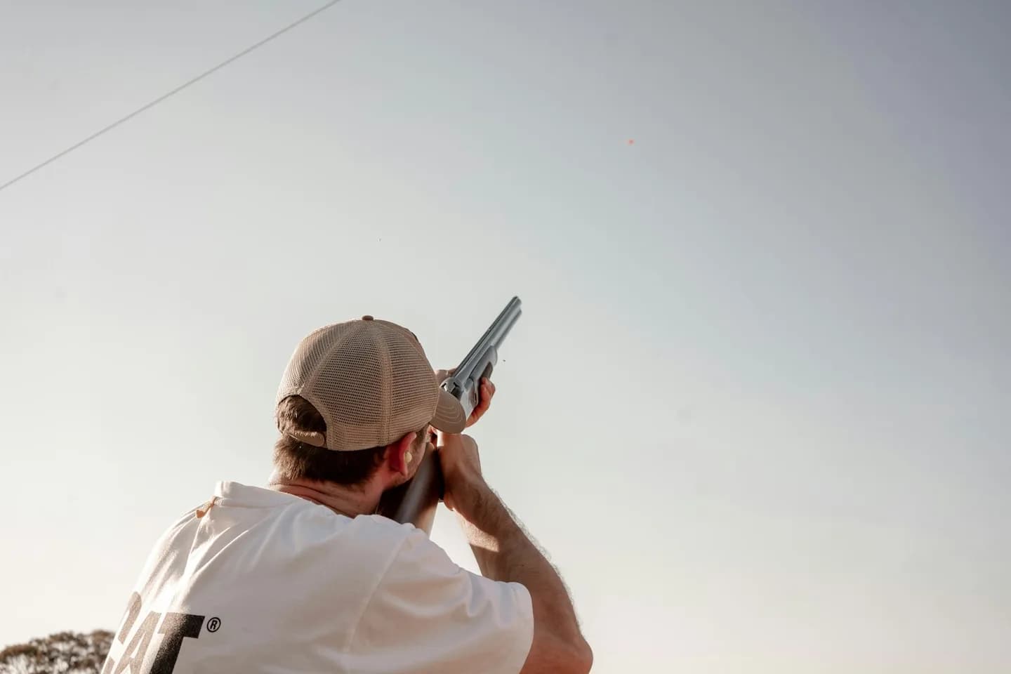 A person taking aim at a clay target against the sky
